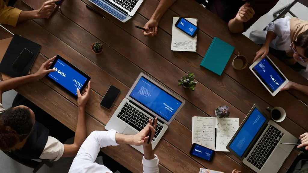 a small group of people discussing figures around a table with their laptops and tables. NorthStar Consulting UK
