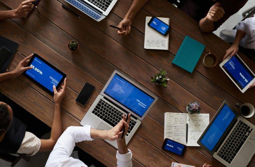 a small group of people discussing figures around a table with their laptops and tables. NorthStar Consulting UK