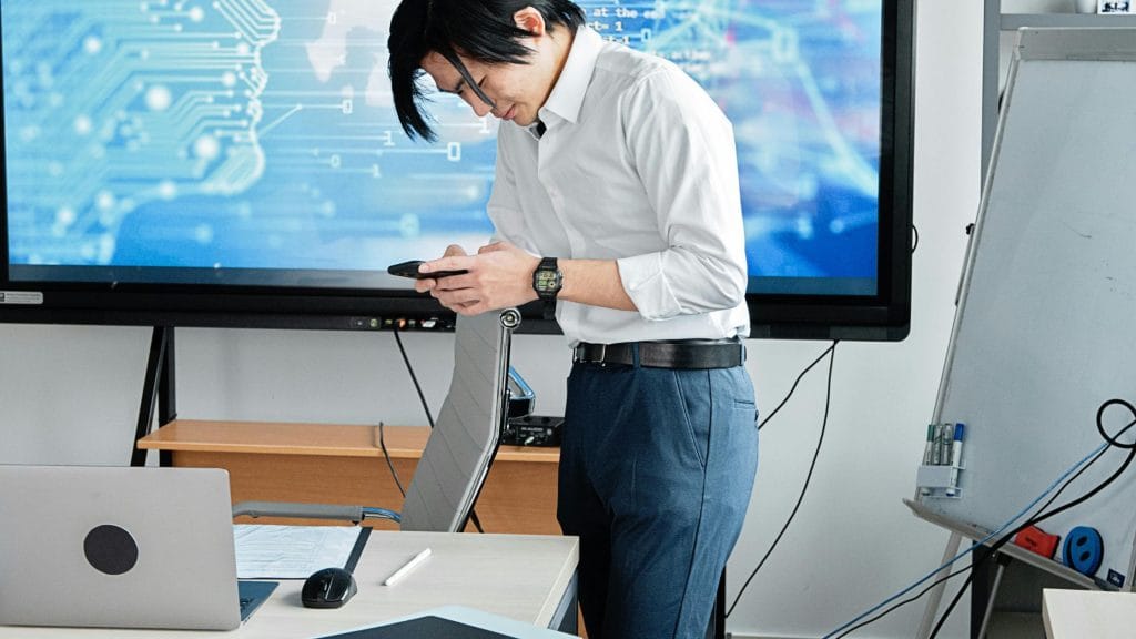 A business professional using AI tools in a modern workspace with digital trade and data visualisation in the background