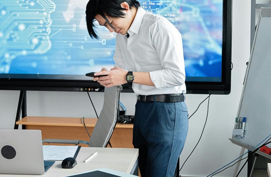 A business professional using AI tools in a modern workspace with digital trade and data visualisation in the background