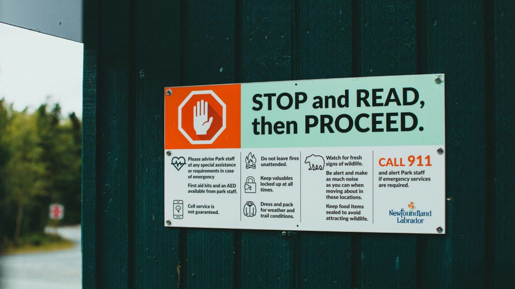 A safety sign reading 'STOP and READ, then PROCEED', serving as a visual metaphor for the necessity of pausing to establish robust AI governance and compliance frameworks before deployment.