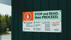 A safety sign reading 'STOP and READ, then PROCEED', serving as a visual metaphor for the necessity of pausing to establish robust AI governance and compliance frameworks before deployment.
