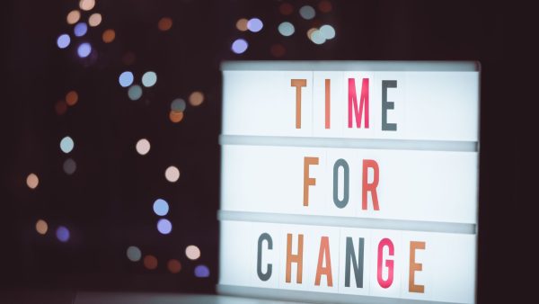 A brightly lit cinematic lightbox displaying the phrase "TIME FOR CHANGE" against a dark background with bokeh lights.