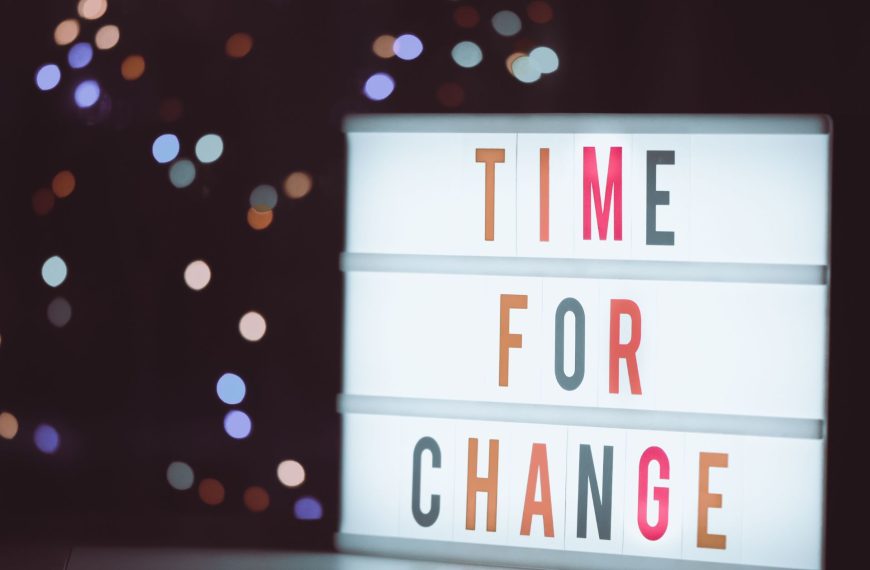 A brightly lit cinematic lightbox displaying the phrase "TIME FOR CHANGE" against a dark background with bokeh lights.