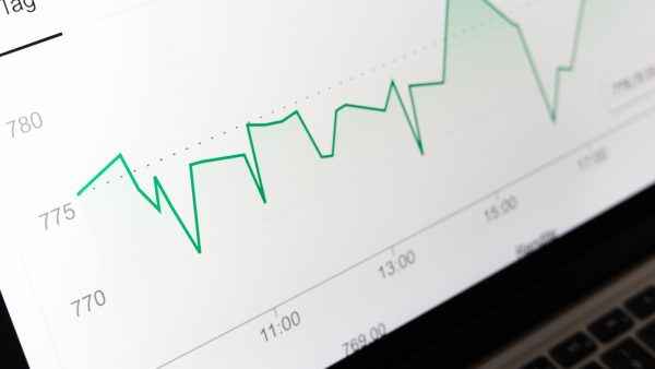A laptop screen displays a green line graph tracking AI search visibility and commercial performance metrics.