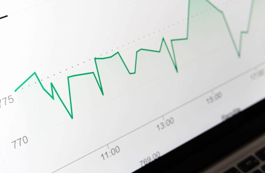 A laptop screen displays a green line graph tracking AI search visibility and commercial performance metrics.